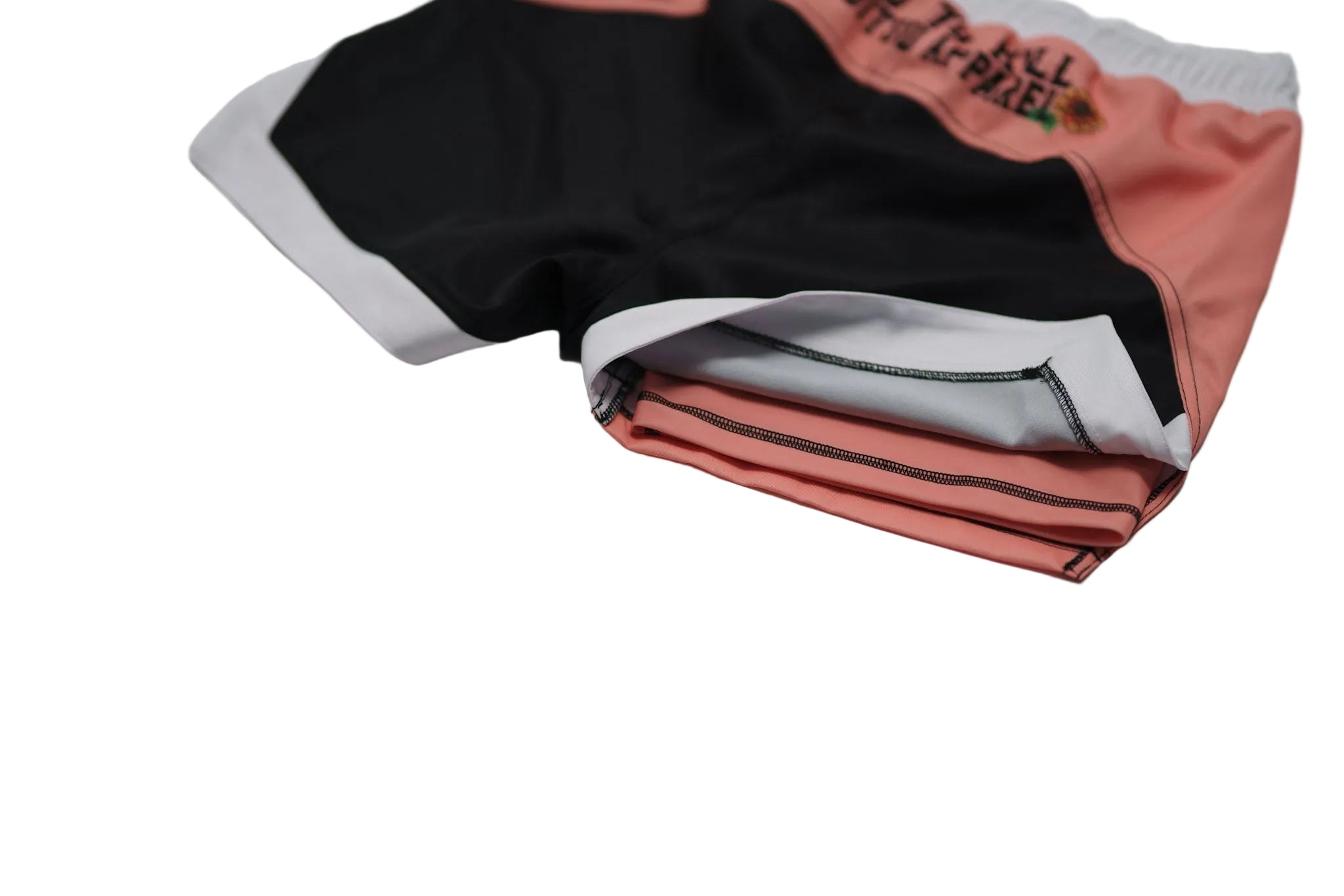 Folded shorts with black, white, and pink colors on a light gray background